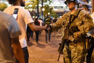 Un manifestantee saluda a un efectivo de la Guardia Nacional anoche durante una manifestación por las calles del centro de Charlotte, Carolina del Norte. El gobernador de Carolina del Norte Pat McCrory declaró estado de emergencia después que centenares de personas se tomaran las calles de la ciudad durante dos dias, en protesta por la muerte del afroamericano Keith Lamont Scott, a manos de la policía. EFE