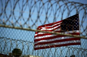 Fotografía de archivo del 14 de septiembre de 2005, que muestra una bandera estadounidense junto a un alambrado en un perímetro de seguridad en Campo Delta 5, en una estación naval de EE.UU. en Guantánamo (Cuba). El Gobierno de Estados Unidos informó hoy, 15 de agosto de 2016, del traslado a Emiratos Árabes Unidos (EAU) de 15 presos que estaban internados en la base militar de Guantánamo. EFE/MIKE BROWN